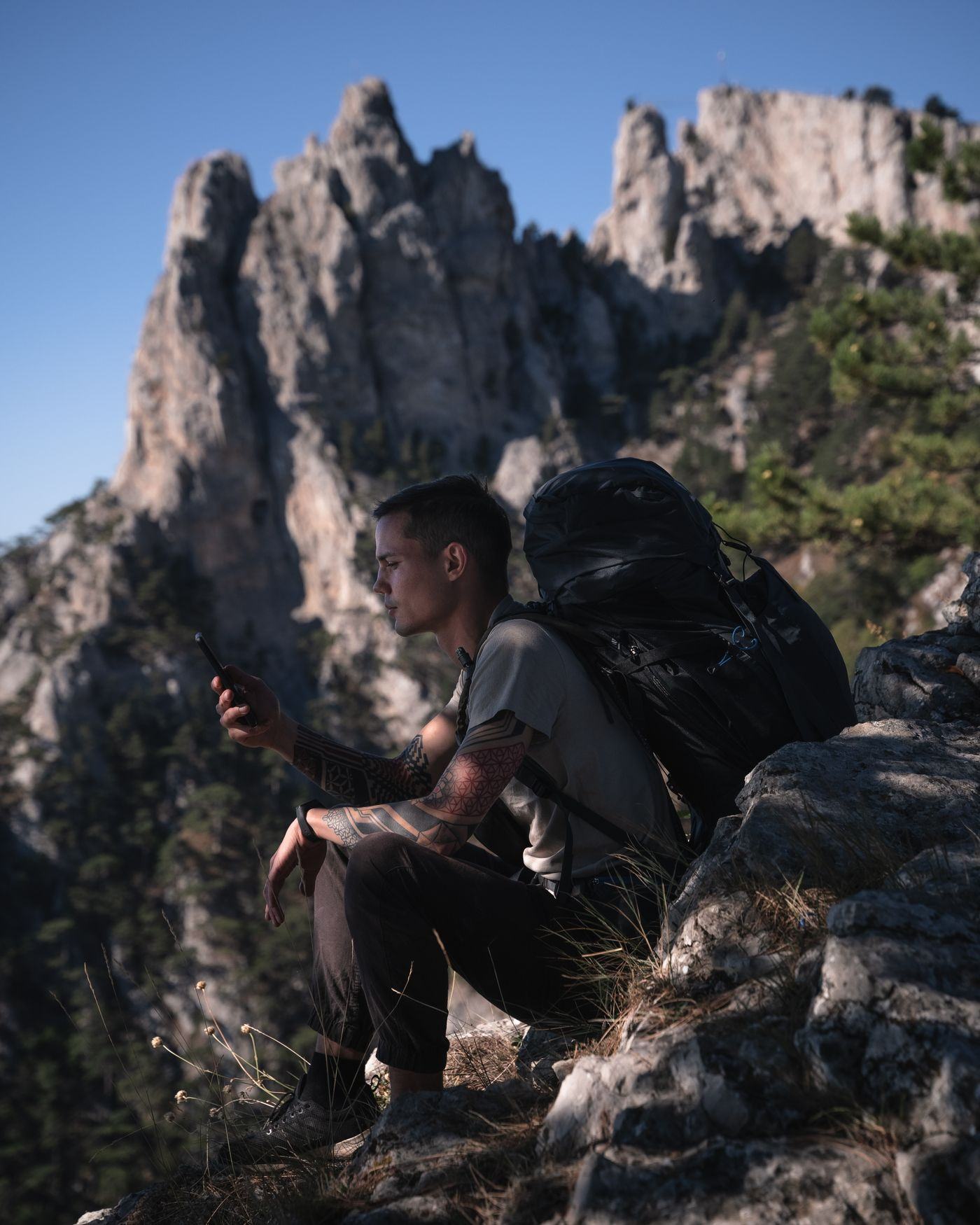 A traveller with a backpack checking a phone on a mountain path