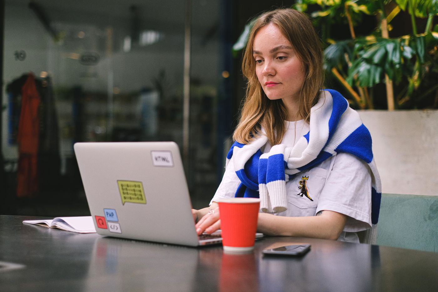 A traveller working from a small cafe table with a laptop and a phone