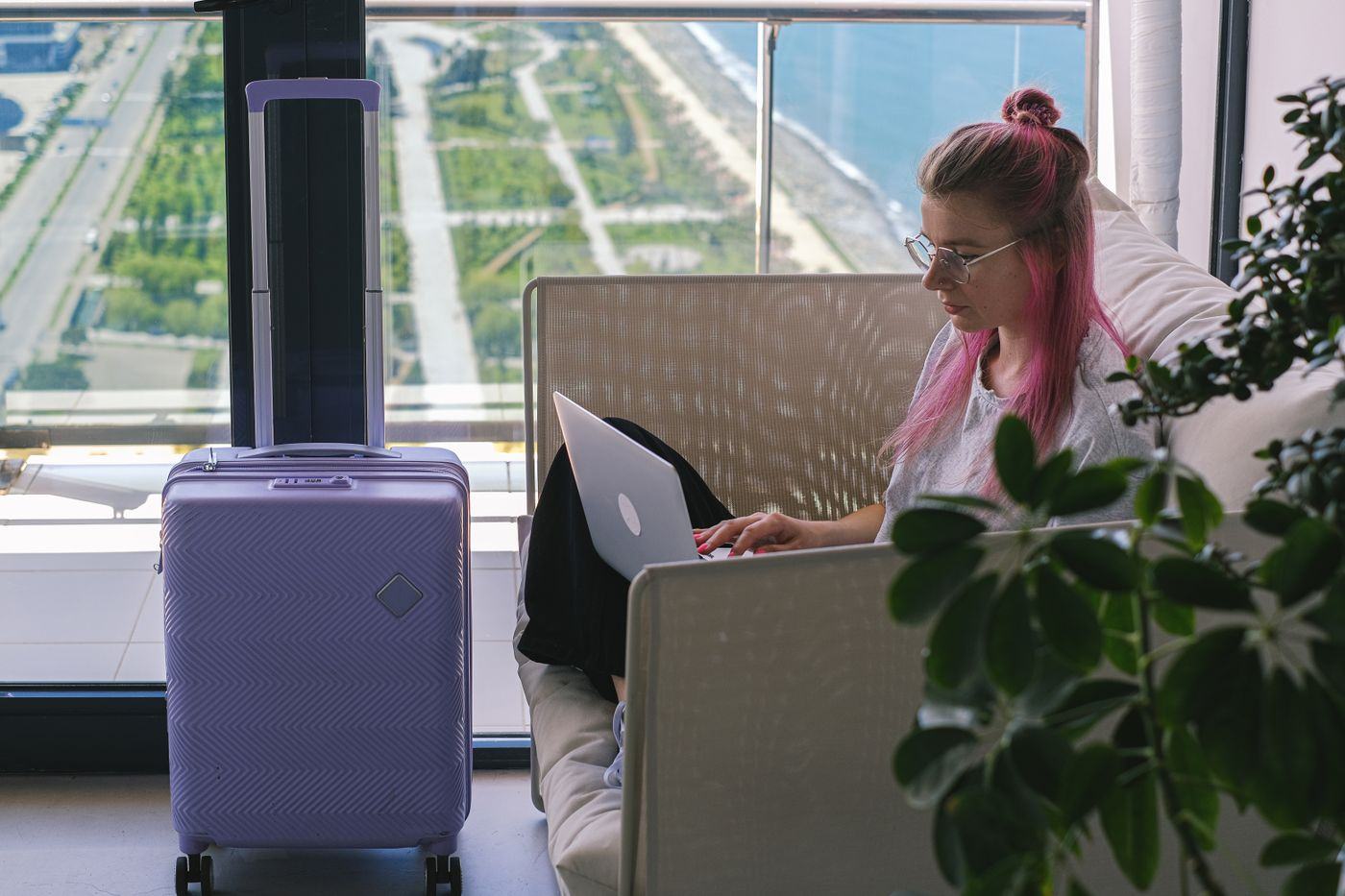 A person working from a hotel room desk with a laptop and a coffee